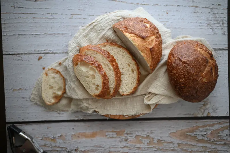 Slices of crusty sourdough bread on a cloth over wooden table, perfect for bakery promotions