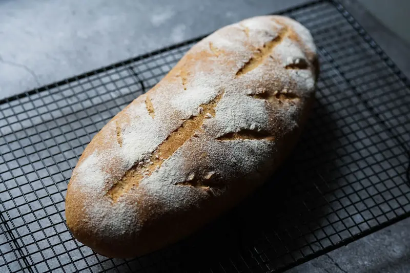 Delicious freshly baked sourdough bread with a crispy crust on a cooling rack in a cozy kitchen setting