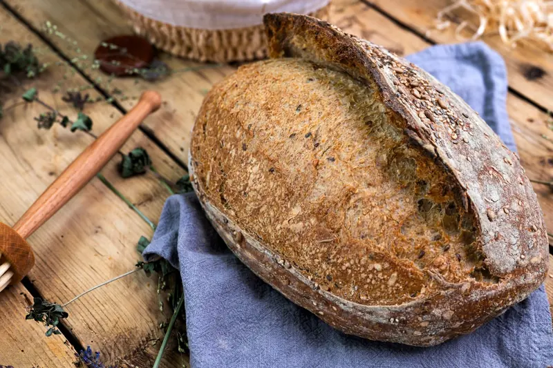 Freshly baked sourdough bread with seeds on a rustic wooden table setting