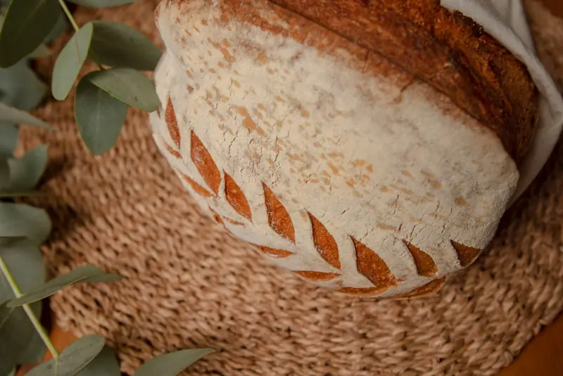 Close-up of crusty artisan bread with decorative scoring on woven placemat