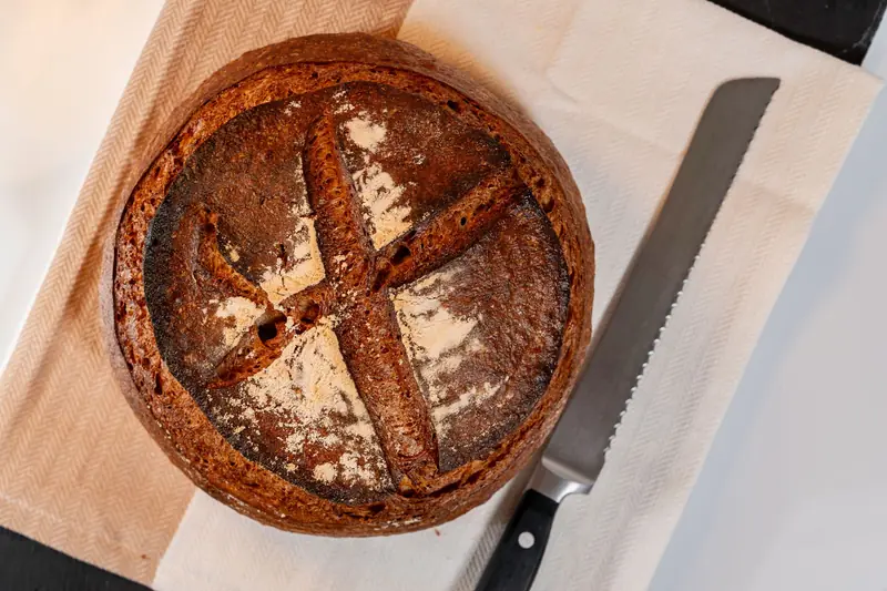 Close-up of a freshly baked artisan sourdough bread loaf with a rustic crust on a cloth with knife